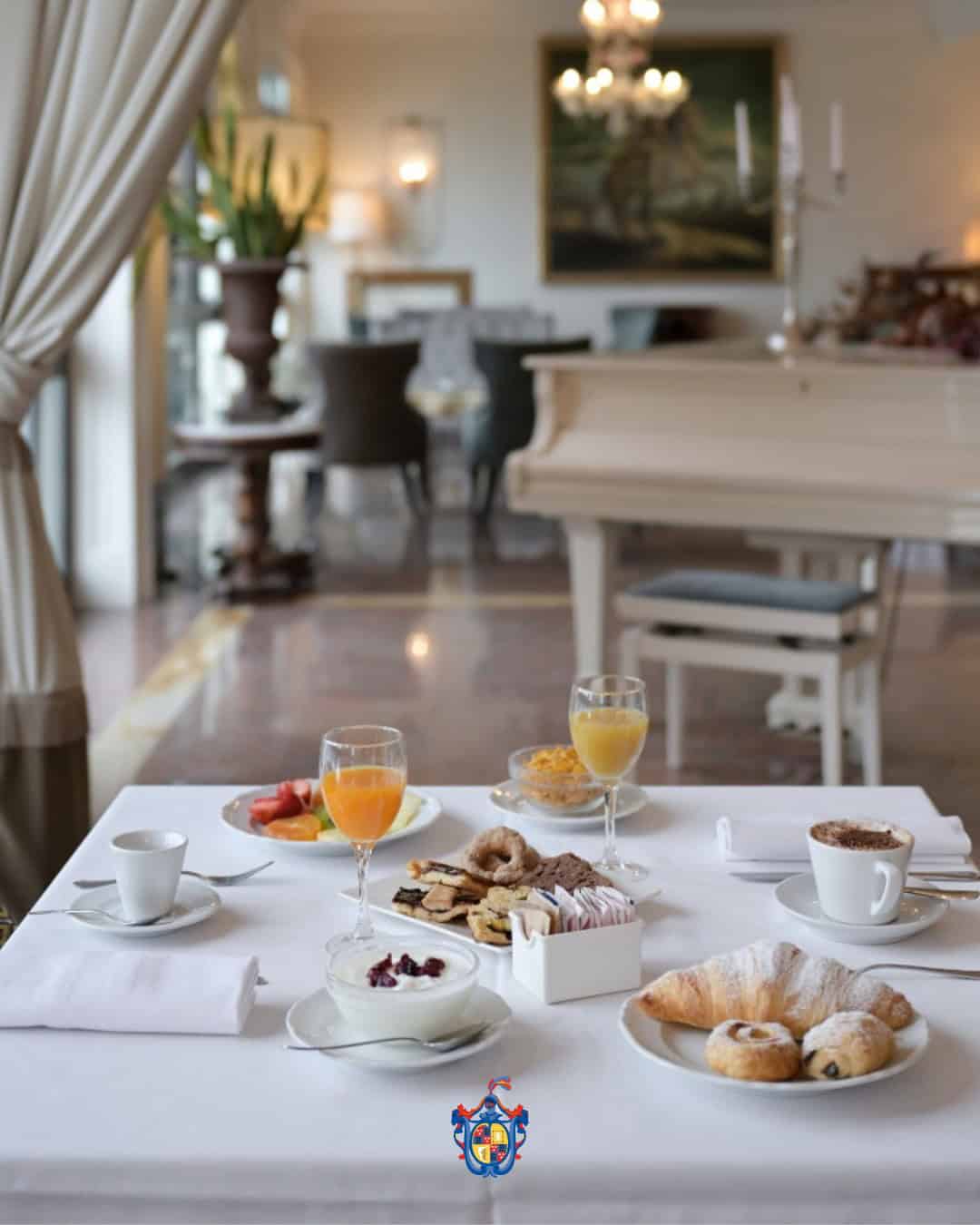Elegant breakfast table with pastries, fruit, coffee, and juice set in a bright, luxurious dining room with a piano—perfect for starting your 4 days in Castel Gandolfo.
