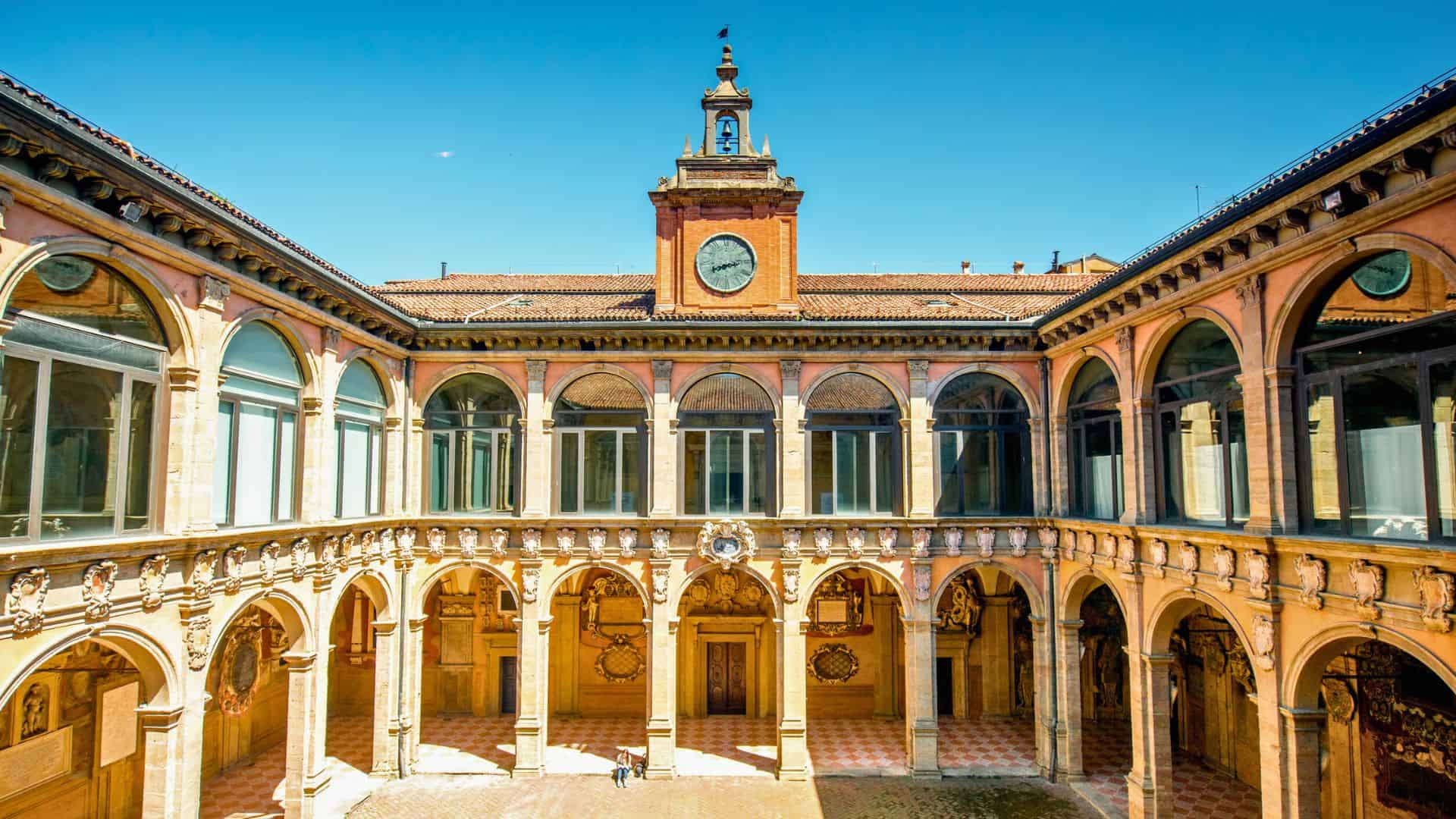 Renaissance courtyard with arched windows and a clock tower under a clear blue sky.