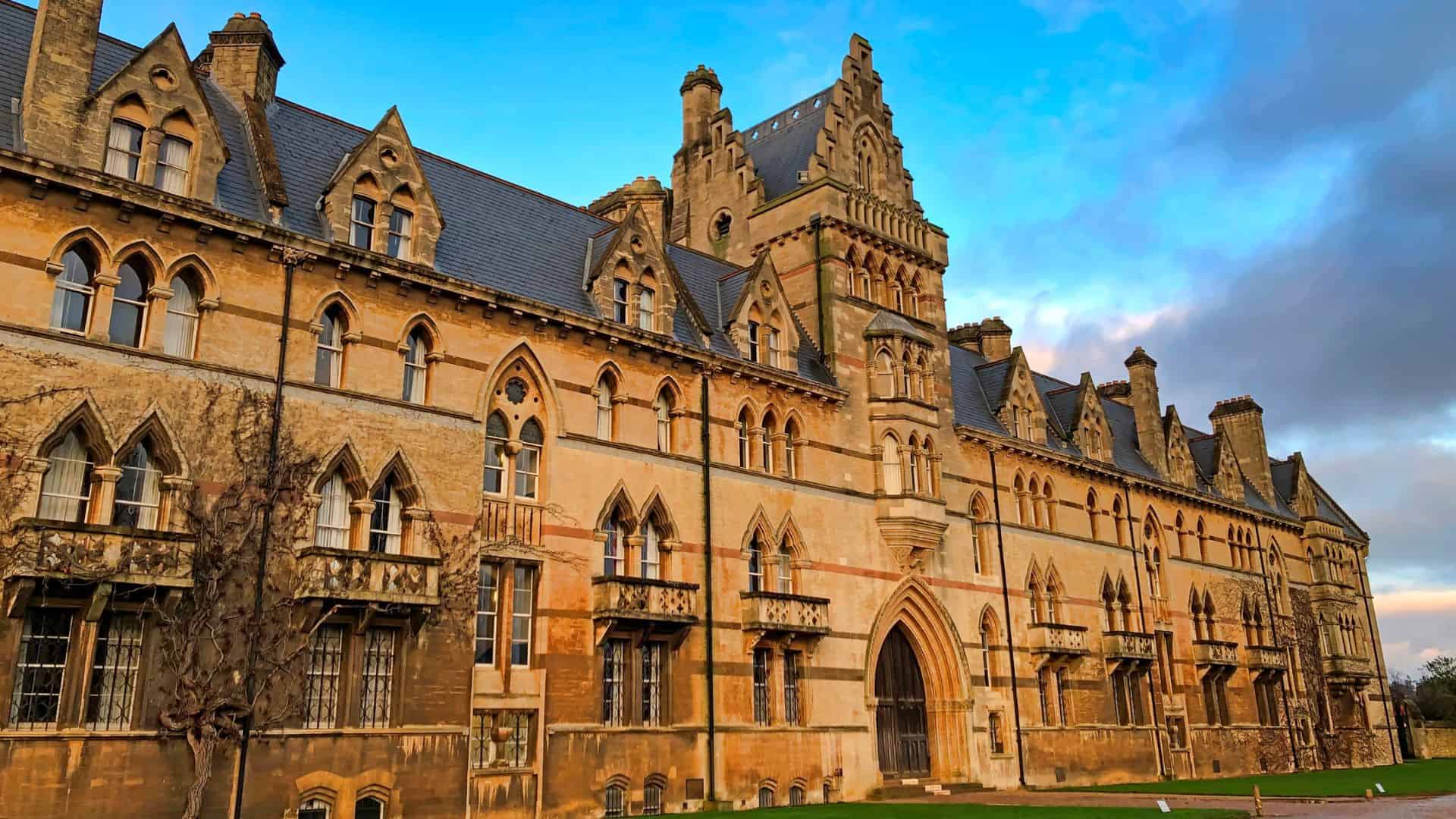 A large, historic stone building with arched windows and ornate gothic architecture under a blue sky.