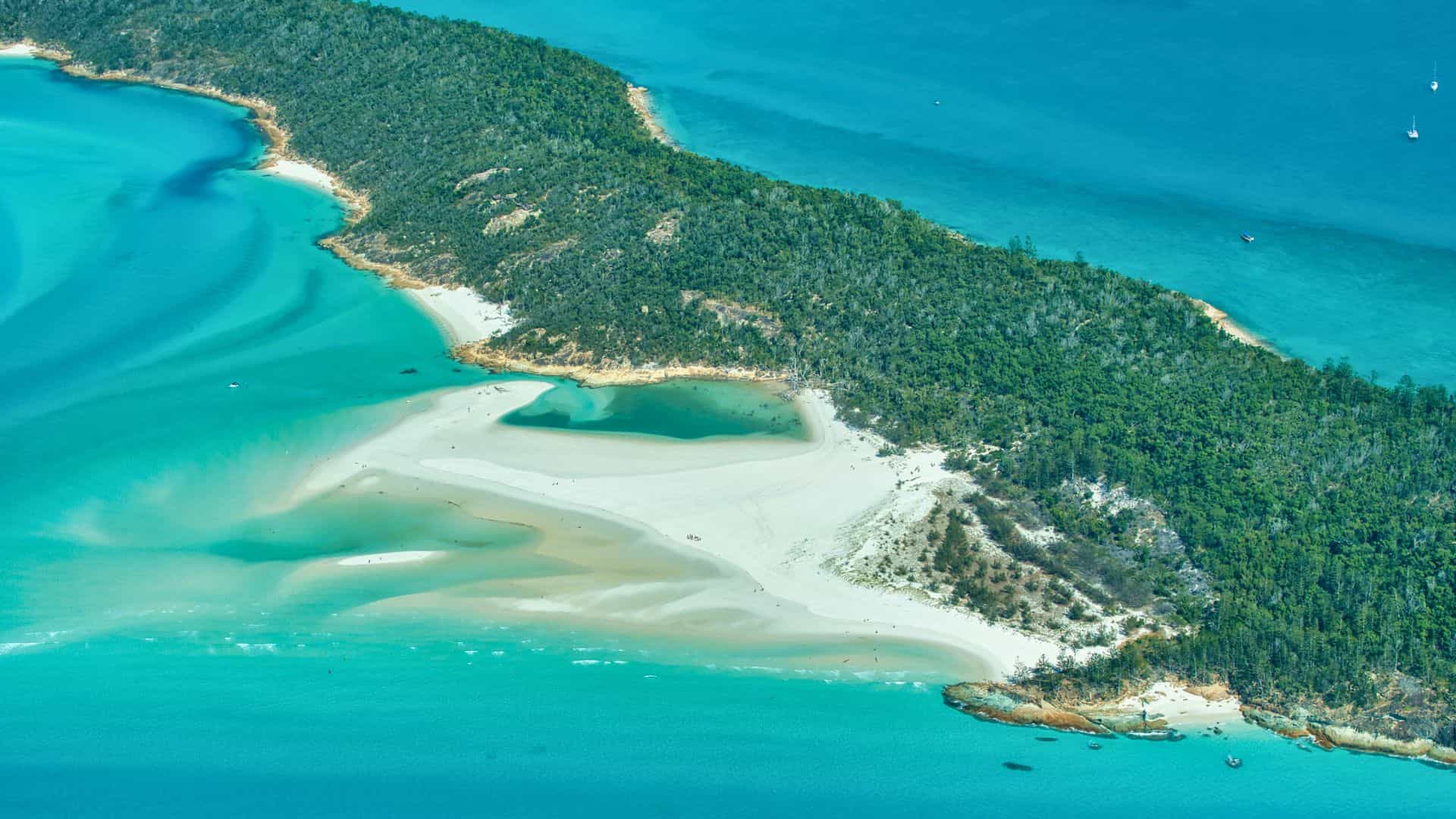 Aerial view of a lush island with white sandy beaches and turquoise blue water.