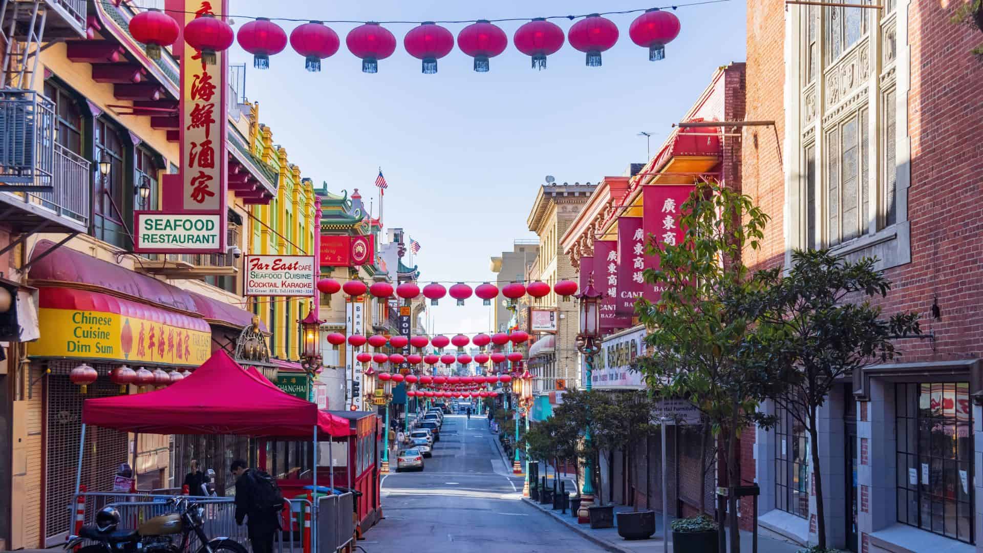 A street in Chinatown decorated with red lanterns, Chinese signs, and shops lining both sides.