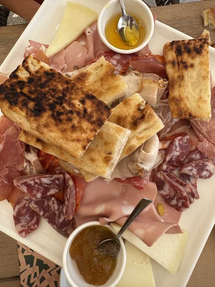 A platter of assorted cured meats, cheeses, grilled bread, and small bowls of honey and jam—perfect to enjoy after 4 days in Castel Gandolfo.