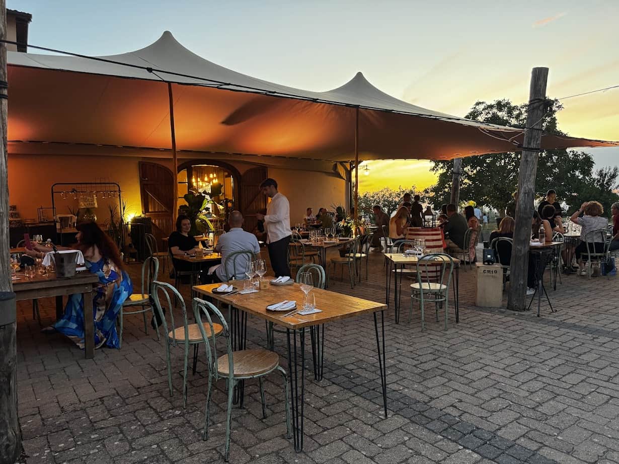 Outdoor restaurant at sunset with people dining under a large canopy and string lights, creating a warm atmosphere&mdash;perfect for unwinding after exploring 4 days in Castel Gandolfo.