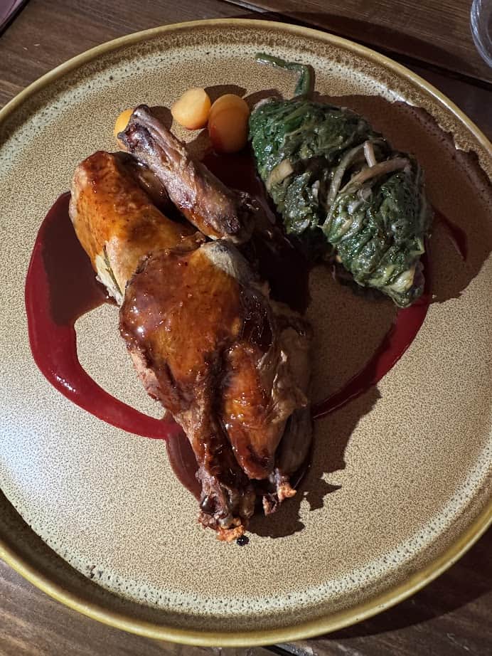 Enjoy a meal reminiscent of 4 days in Castel Gandolfo: roast chicken with brown sauce, three melon balls, and a spinach omelette, all beautifully presented on a tan plate.