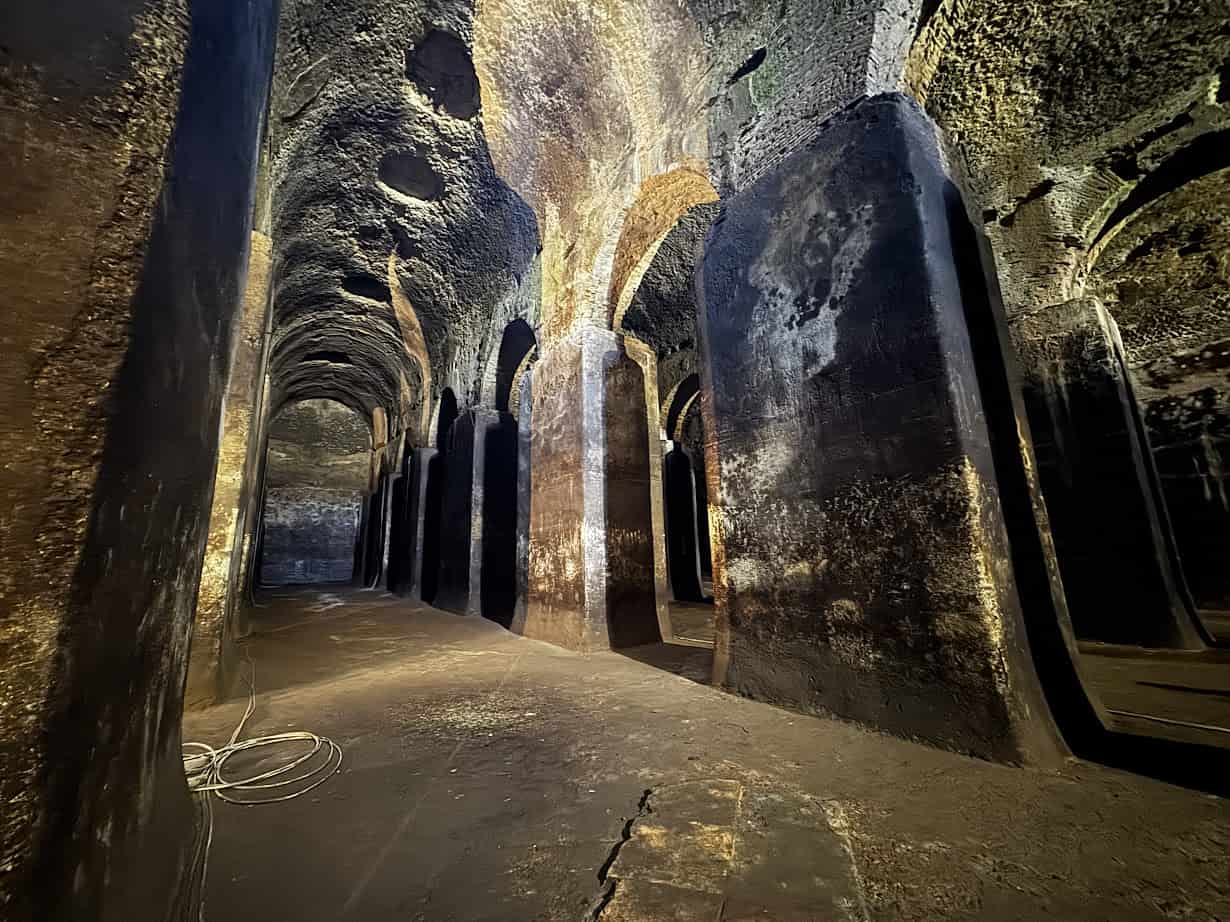 Ancient stone hallway with high arched ceilings and tall pillars, dimly lit with natural and artificial light—an atmosphere you might encounter during 4 days in Castel Gandolfo.