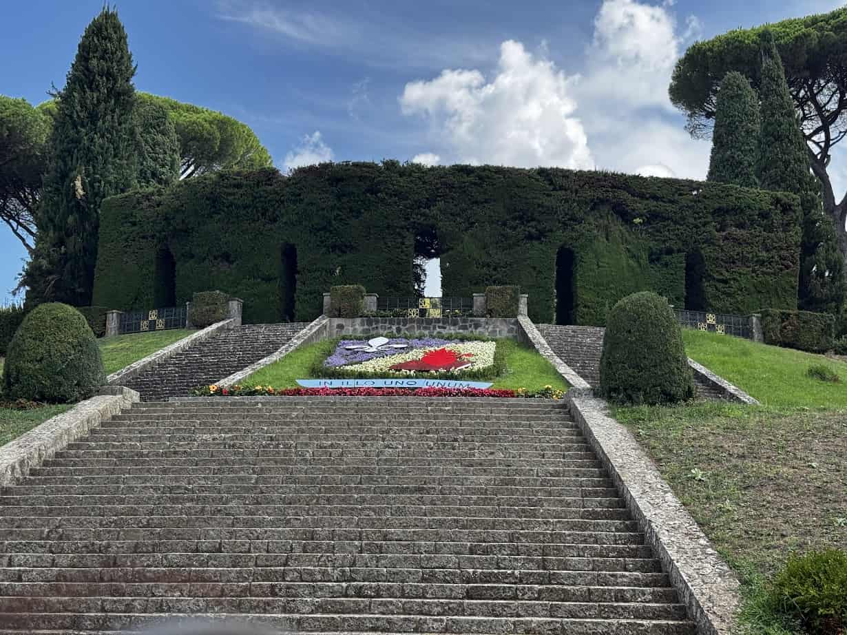 Stone steps lead to a hedge archway with manicured bushes and a colorful flower arrangement in the center—a charming scene you might discover during 4 days in Castel Gandolfo.