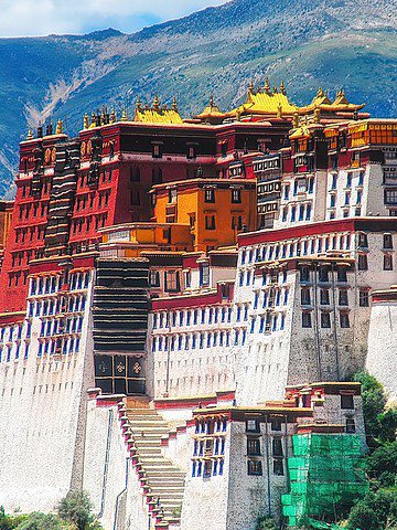 The Potala Palace in Tibet, a large, colorful structure set against green mountains and a blue sky.