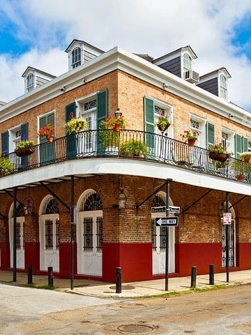 A corner building with a balcony and colorful flags in the French Quarter of New Orleans.