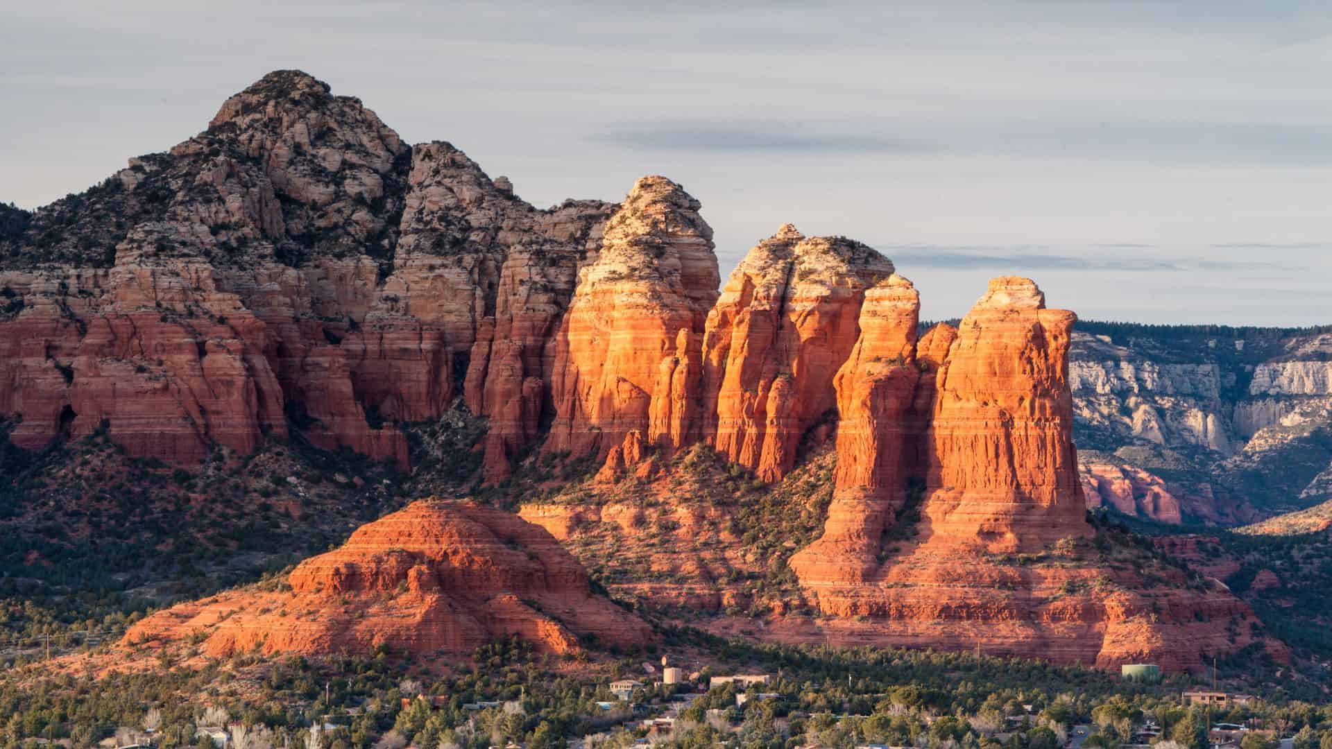 Red rock formations at Cathedral Rock in Sedona, Arizona, lit by the sunlight with blue sky in the background.