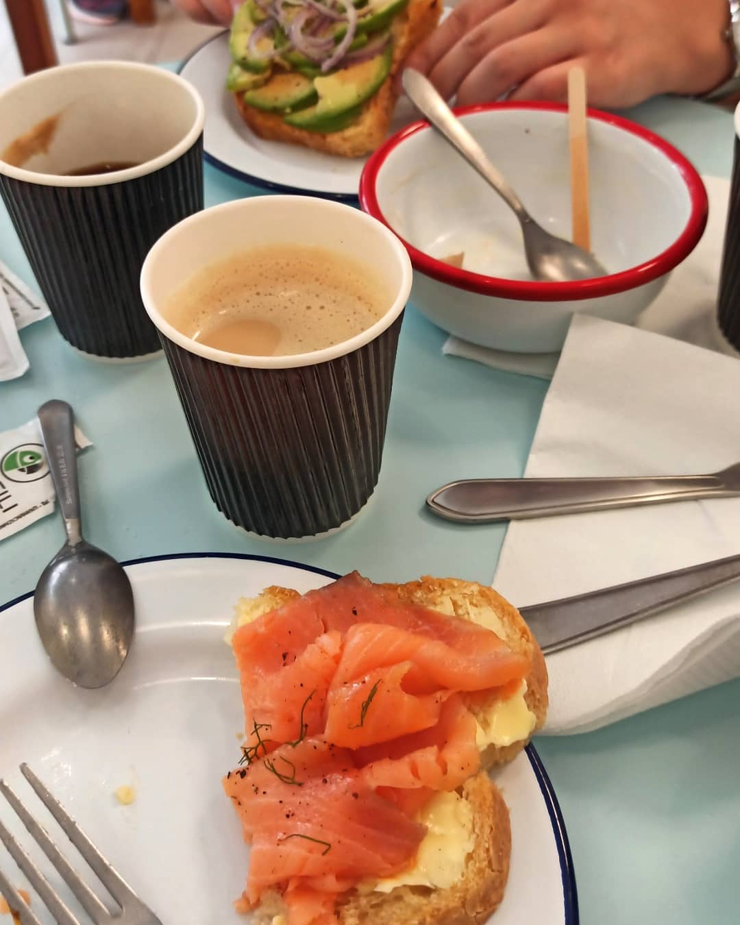 A plate with smoked salmon toast, coffee cups, and an empty bowl on a table set for breakfast at one of the top Gluten Free Restaurants in Rome.