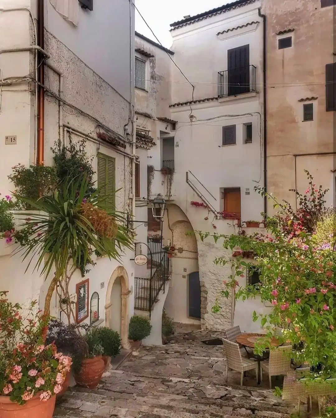 A charming stone courtyard with potted plants, flowers, and white Mediterranean-style buildings&mdash;perfect for relaxing during one of the best day trips from Rome for families.