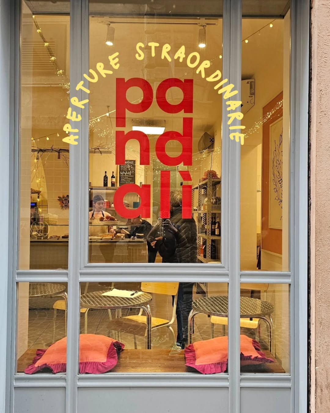 Cafe window with "pandali" in red letters and yellow "aperture straordinarie" above; a welcoming spot among Gluten Free Restaurants in Rome, with tables and chairs inside.