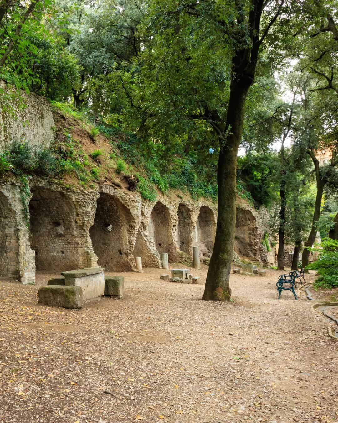Stone benches and ancient arched niches amid trees create a peaceful, shaded park&mdash;an ideal spot included in the best day trips from Rome for families seeking relaxation and history together.