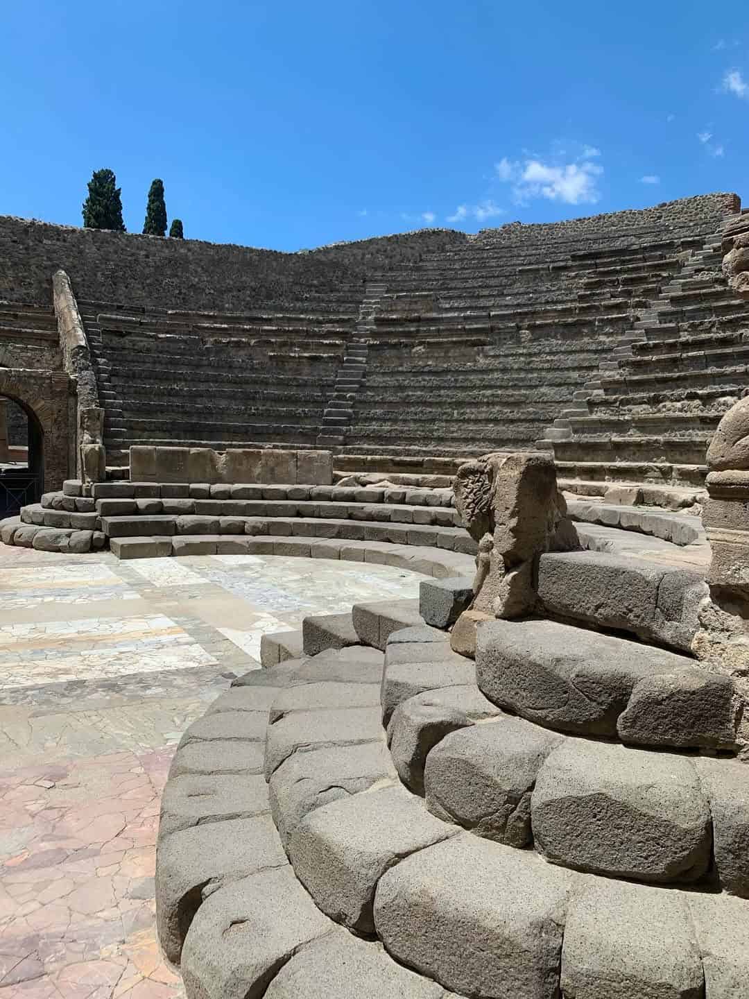 Ancient stone amphitheater with tiered seating under a bright blue sky, perfect for one of the best day trips from Rome for families.
