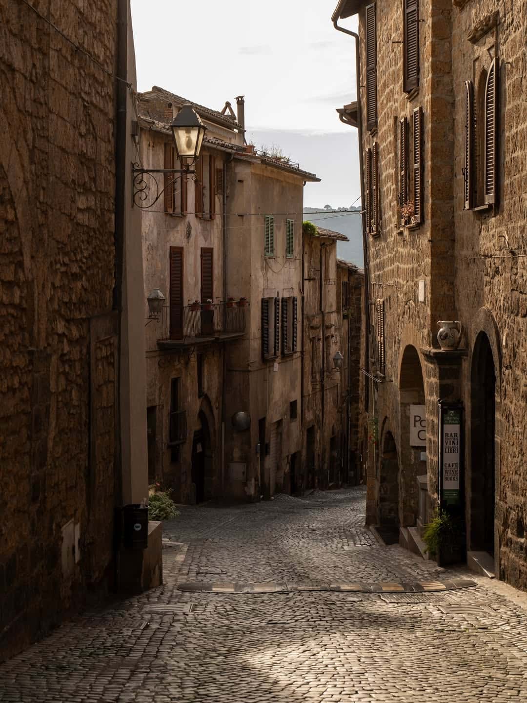 Narrow cobblestone street lined with old stone buildings and shuttered windows in a historic European town&mdash;perfect for those seeking the best day trips from Rome for families.