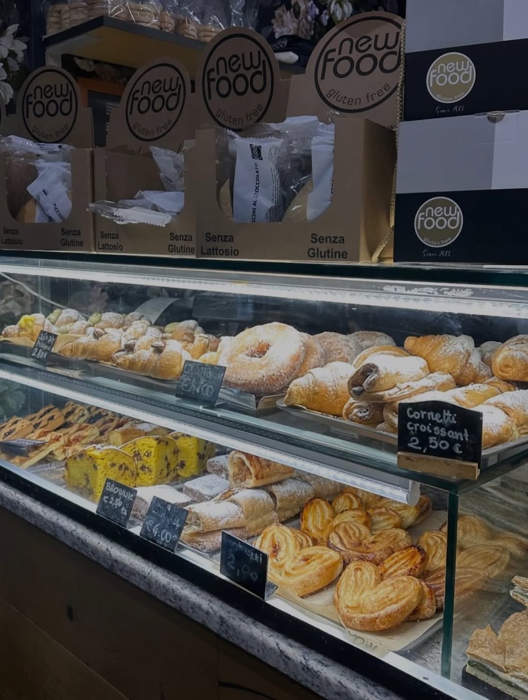 Glass bakery display filled with assorted pastries, breads, and labeled gluten-free packaged products above—perfect for those seeking options similar to Gluten Free Restaurants in Rome.