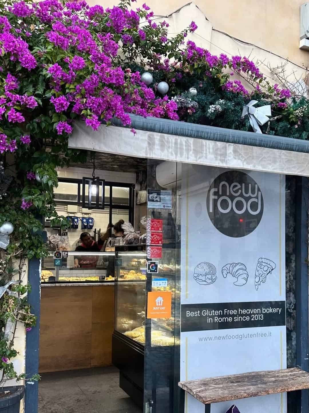 Bakery entrance with glass door, floral awning, and a sign for "Best Gluten Free bakery in Rome since 2013"—a charming highlight among Gluten Free Restaurants in Rome.