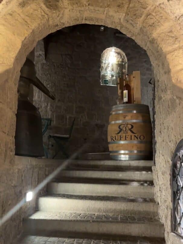 Stone archway and stairs lead up to a wine barrel labeled "Ruffino" in a rustic cellar—perfect inspiration for savoring 4 days in Castel Gandolfo.