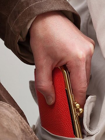 A hand is stealing a red wallet from the pocket of a person wearing a light-colored coat.