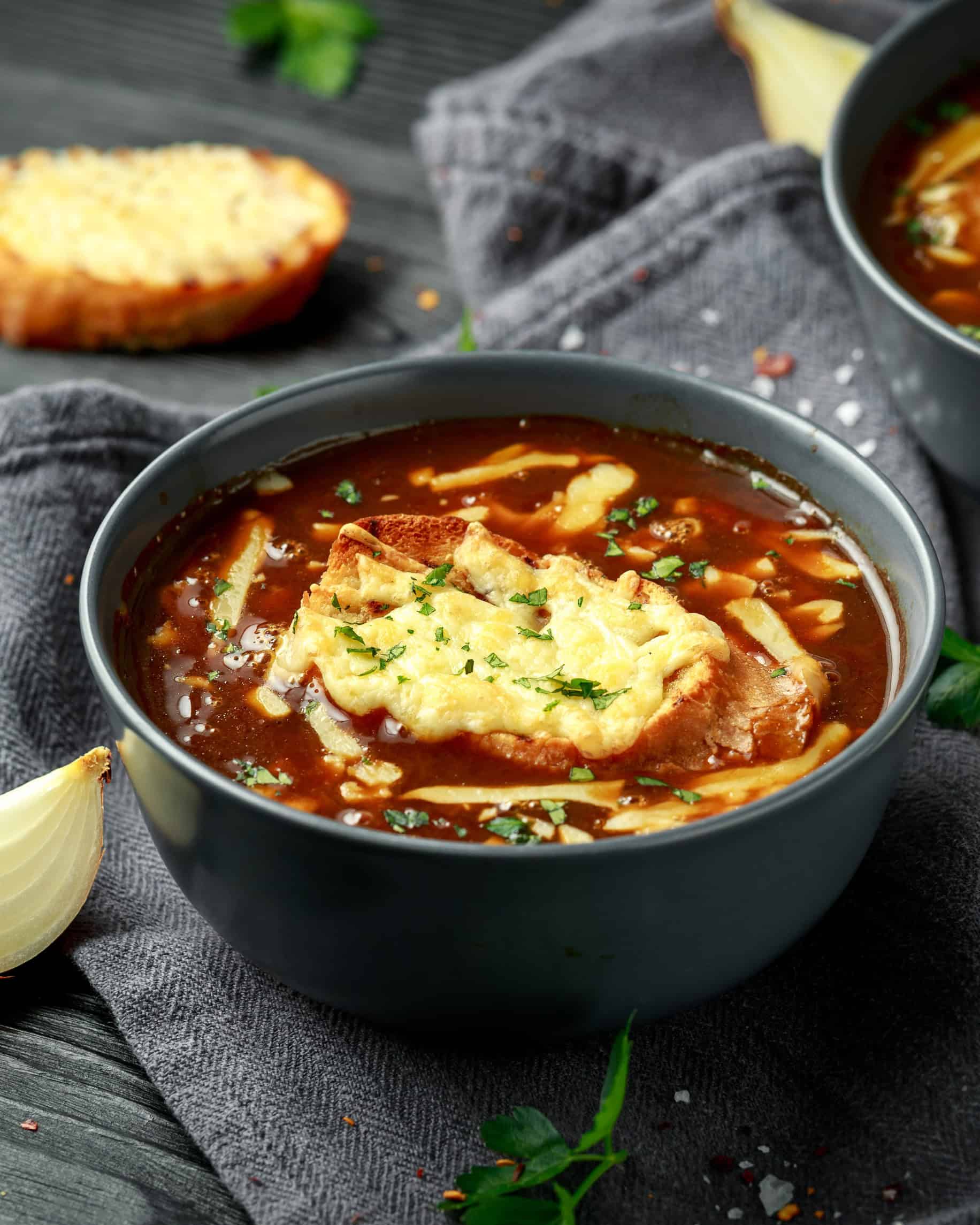 A bowl of French onion soup topped with melted cheese and bread, garnished with herbs&mdash;a classic among the Best Vegetarian Food in France.