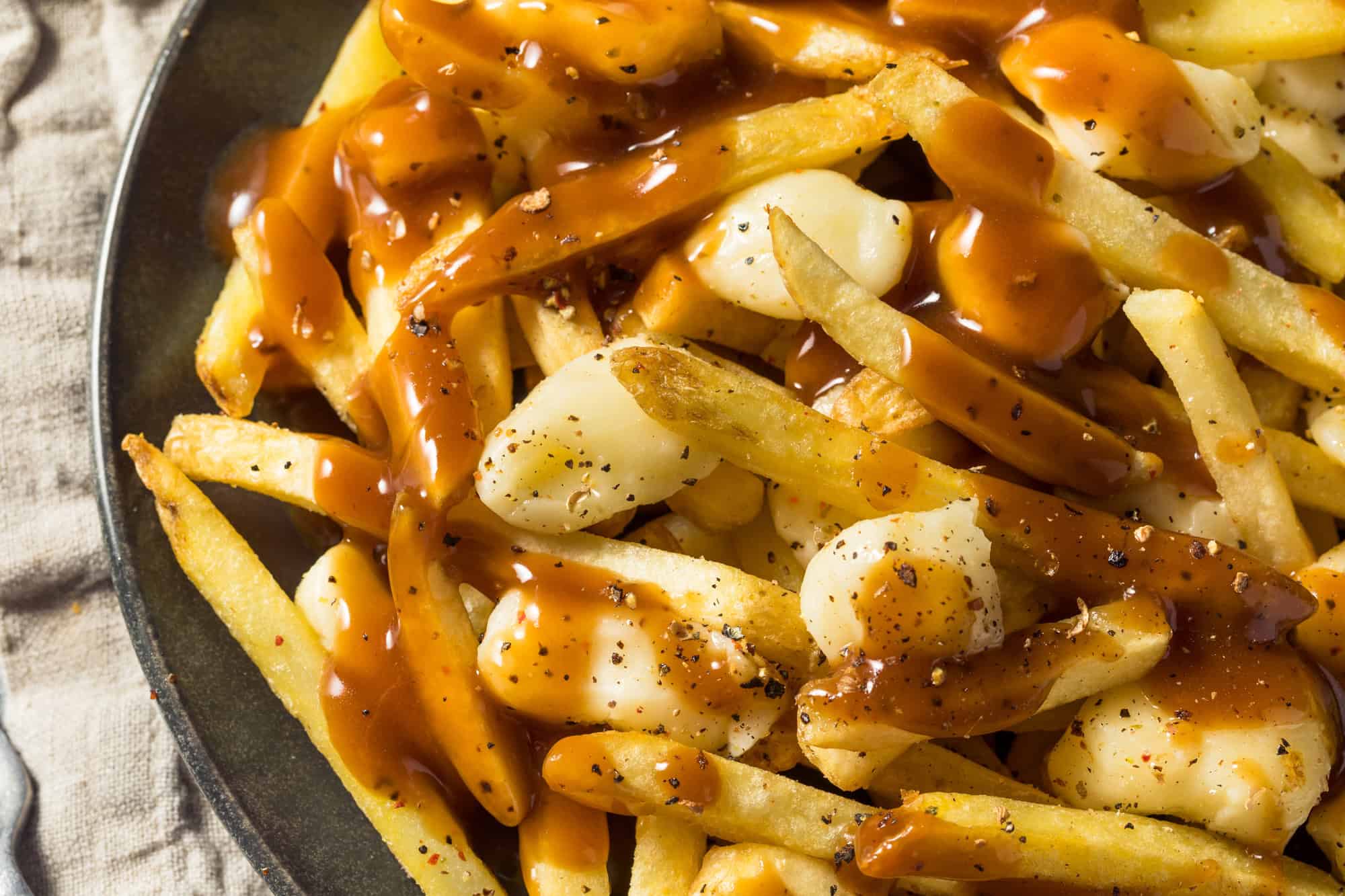 French fries topped with cheese curds and brown gravy on a plate, this classic poutine dish is a delicious highlight among Canadian Vegetarian Dishes.