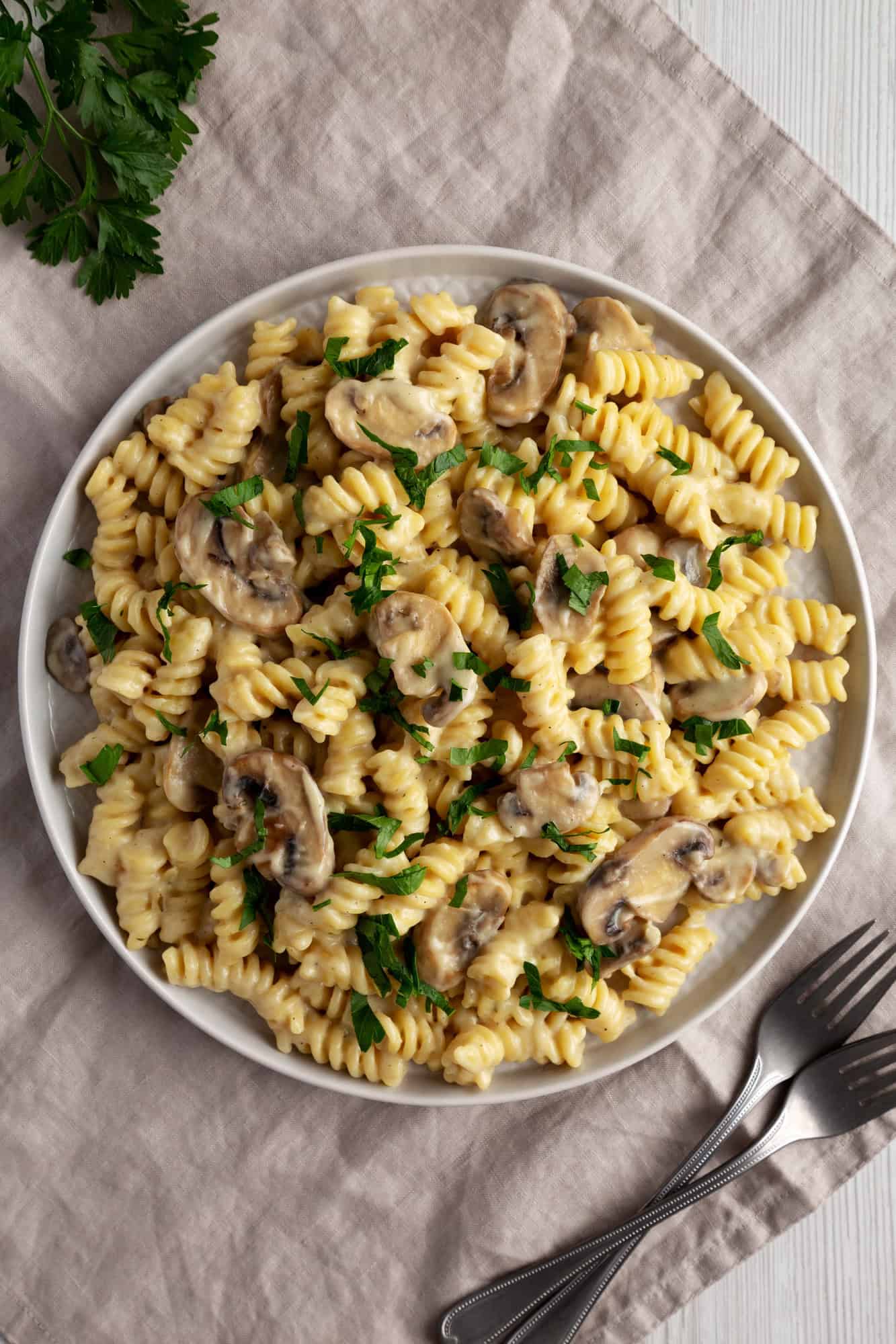 A plate of creamy mushroom pasta, a standout among Canadian Vegetarian Dishes, garnished with parsley and served with a fork and knife.