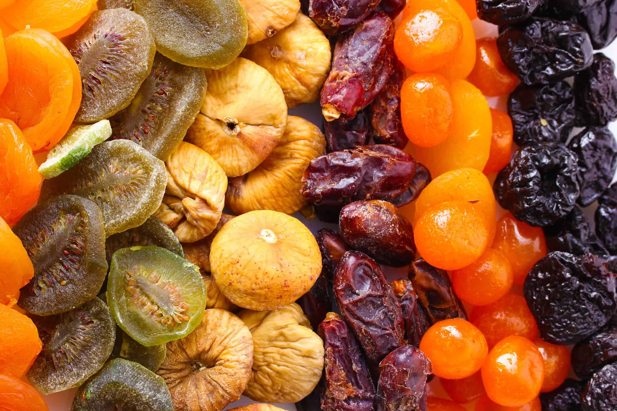 Assorted dried fruits including apricots, kiwis, figs, dates, prunes, and golden berries, arranged in rows&mdash;a classic display of vegetarian food in Israel.