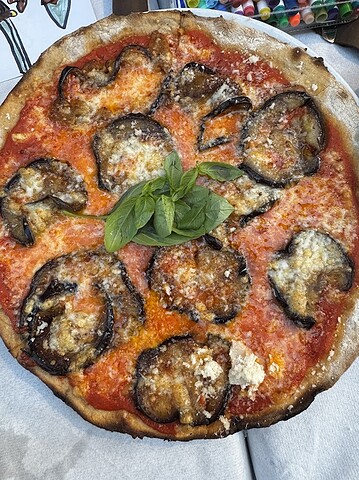 Experience authentic Italian flavor with this pizza topped with roasted eggplant, tomato sauce, cheese, and fresh basil—a delicious way to Eat Vegetarian in Italy.