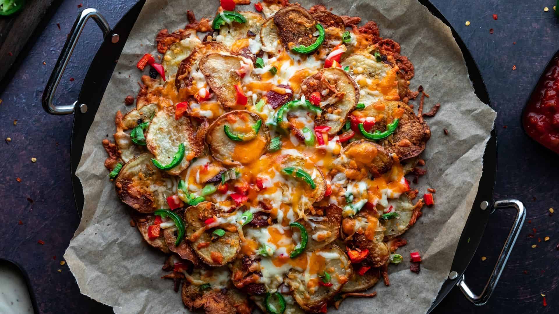 Baked loaded nachos with melted cheese, jalape&ntilde;os, potatoes, and red peppers on parchment paper&mdash;one of the best vegetarian Mexican dishes for any gathering.