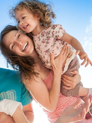 Five smiling people, including two children, pose together against a bright blue sky.