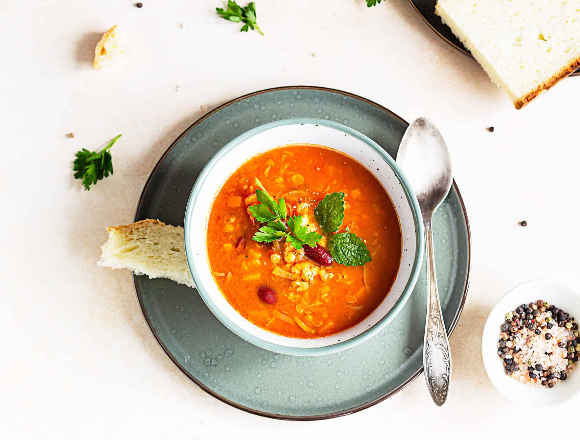 A bowl of Ukrainian vegetable soup with herbs, a classic vegetarian dish, served with bread and a spoon on a plate.