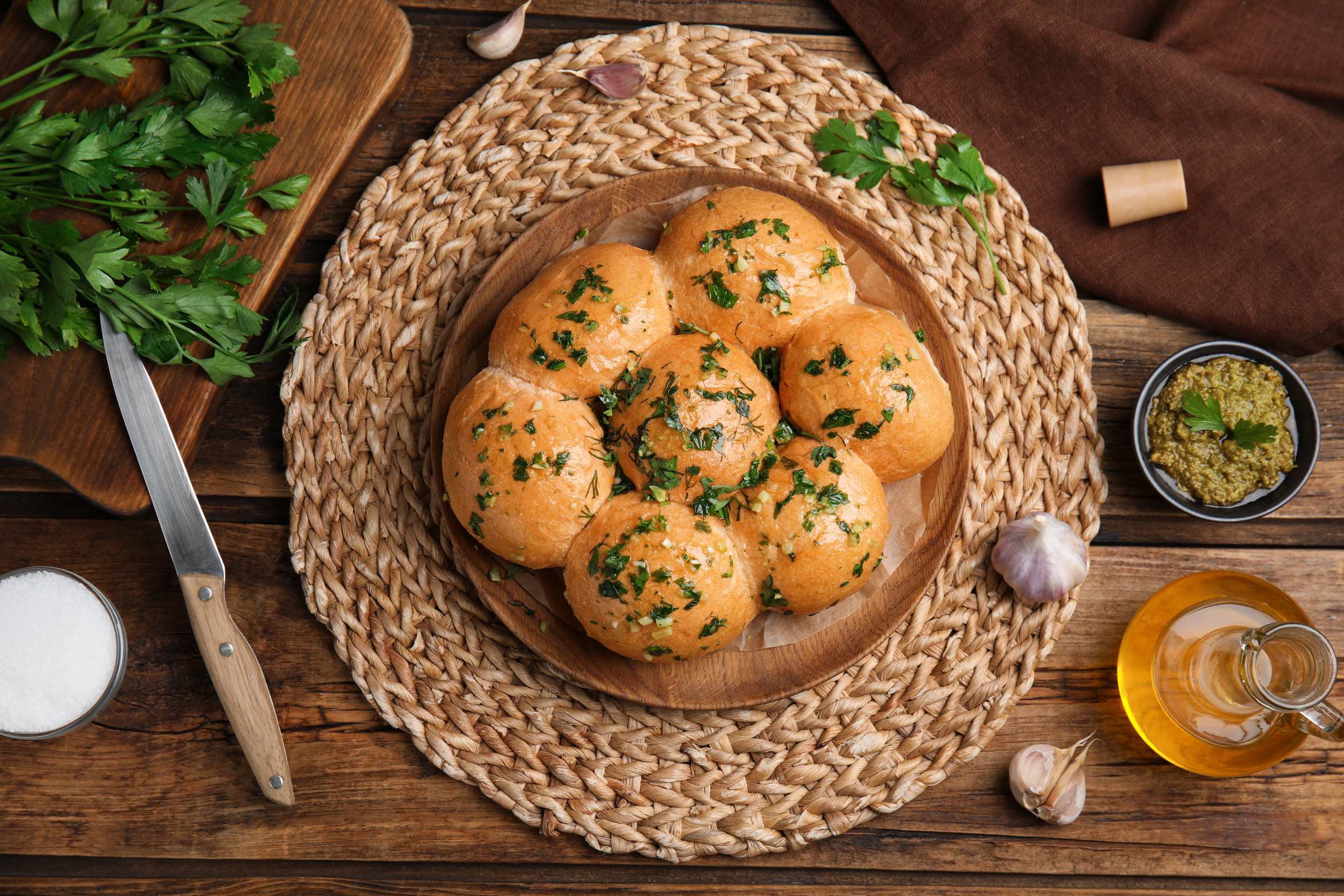 Round bread rolls topped with chopped herbs on a wooden plate, surrounded by parsley, garlic, and olive oil&mdash;a classic from Ukraine, perfect for fans of vegetarian dishes.