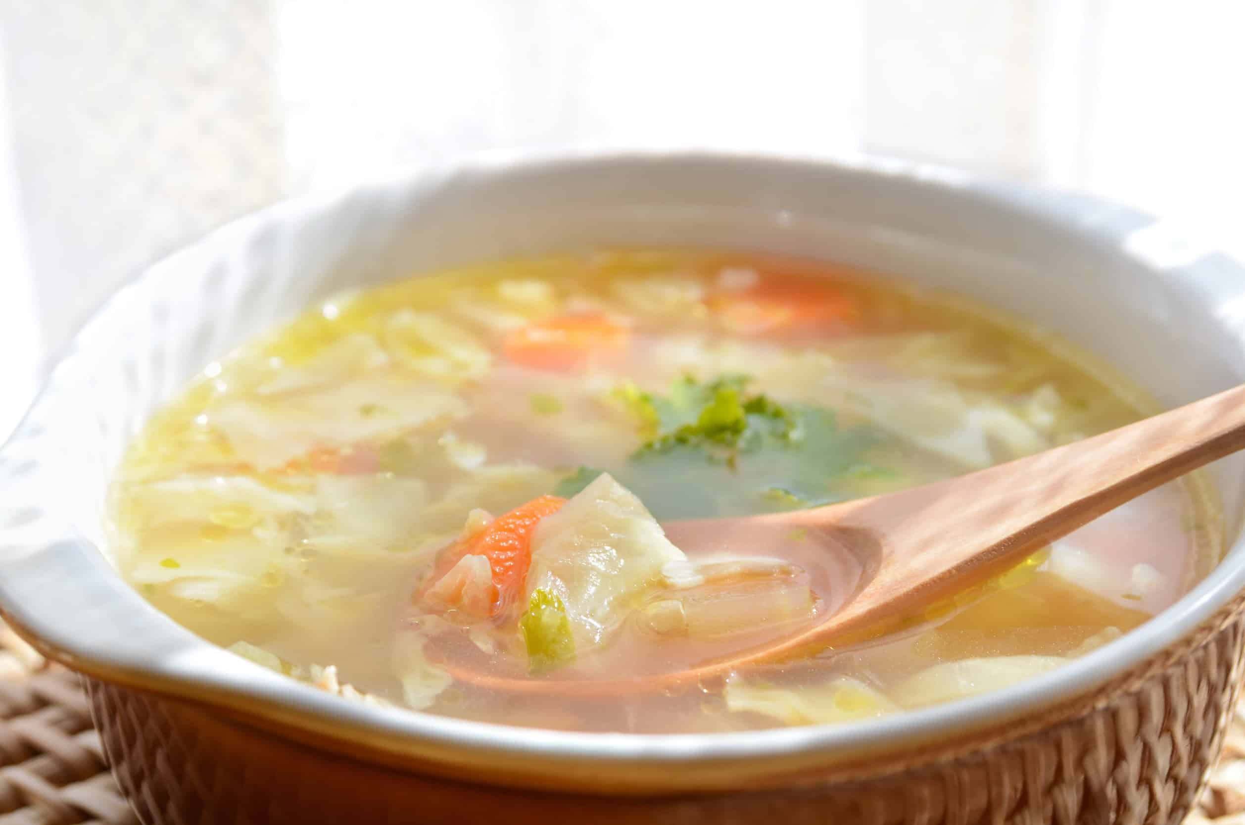 A bowl of delicious Ukrainian vegetable soup with a wooden spoon, showcasing chunks of cabbage, carrot, and broccoli&mdash;an inviting option for fans of vegetarian dishes.