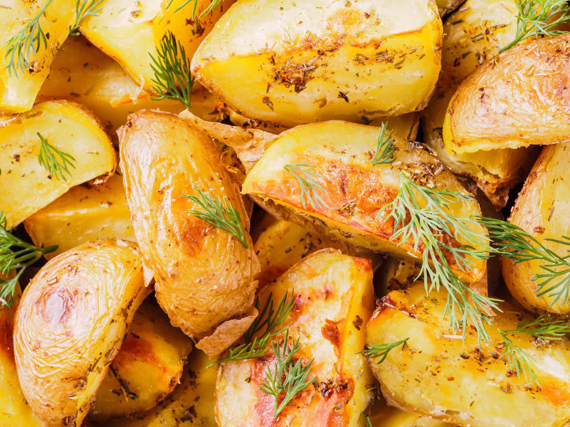 Golden roasted potato wedges with herbs and fresh dill sprinkled on top, a beloved choice among vegetarian dishes in Russia.