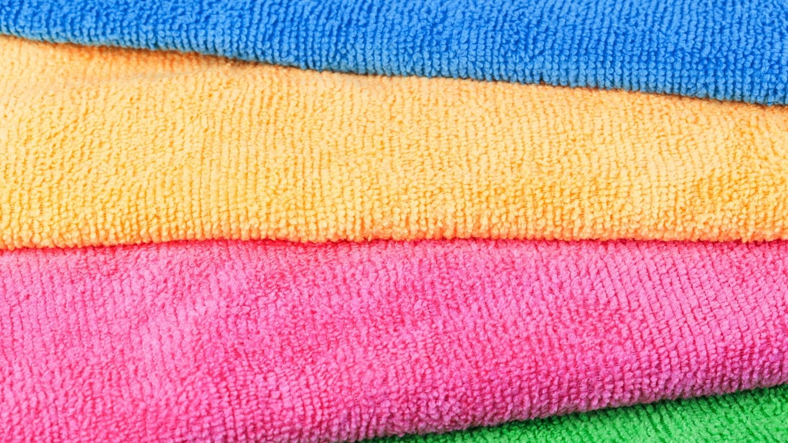 Stack of microfiber cloths in blue, yellow, pink, and green colors, shown in close-up—perfect for hot weather travel or Asia travel hacks thanks to their lightweight and quick-drying qualities.