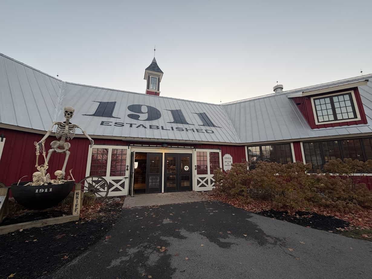 Red barn-style building with "1911 Established" on the roof, a skeleton display, and autumn plants outside—an iconic Finger Lakes stop perfect for a fall road trip or relaxed weekend getaway.