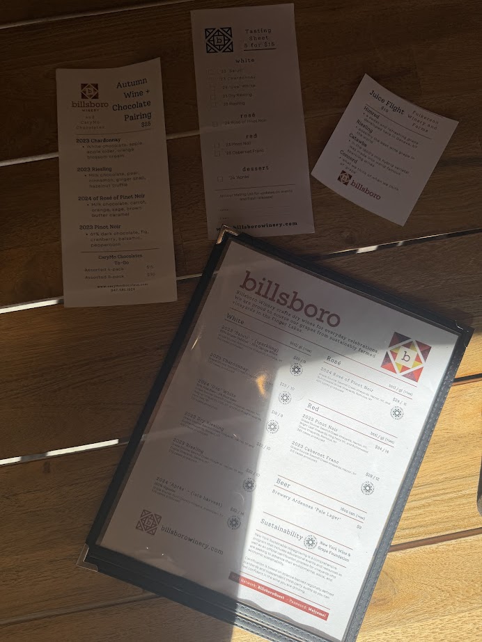 Menus and wine tasting lists from Billsboro Winery, one of the best wineries in Finger Lakes, displayed on a wooden table in sunlight.