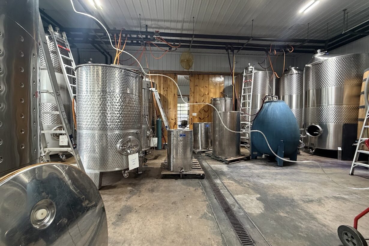 Large stainless steel tanks and equipment inside a modern industrial brewery or distillery facility, reminiscent of the cutting-edge setups found at the best wineries in Finger Lakes.