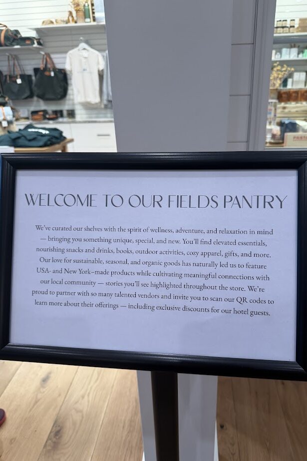 Framed sign in a store with a welcome message for "Our Fields Pantry," info about their Finger Lakes products, and details on partners at Skaneateles Fields Resort.