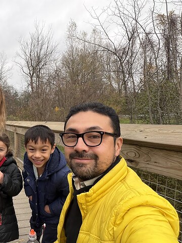 Four people smile on a wooden walkway outdoors at Skaneateles Fields Resort in the Finger Lakes; two adults and two children pose for a cheerful group selfie, capturing memories after a fun day at the spa.