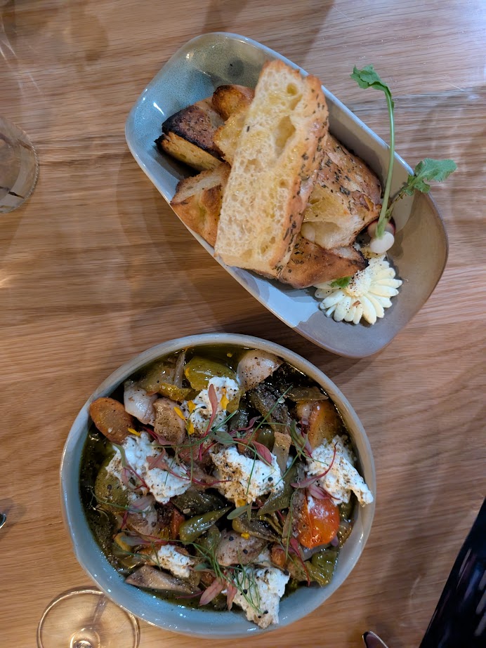 Two bowls: one with toasted bread and butter, the other with burrata cheese, cherry tomatoes, and roasted vegetables—perfect for a Finger Lakes weekend getaway.