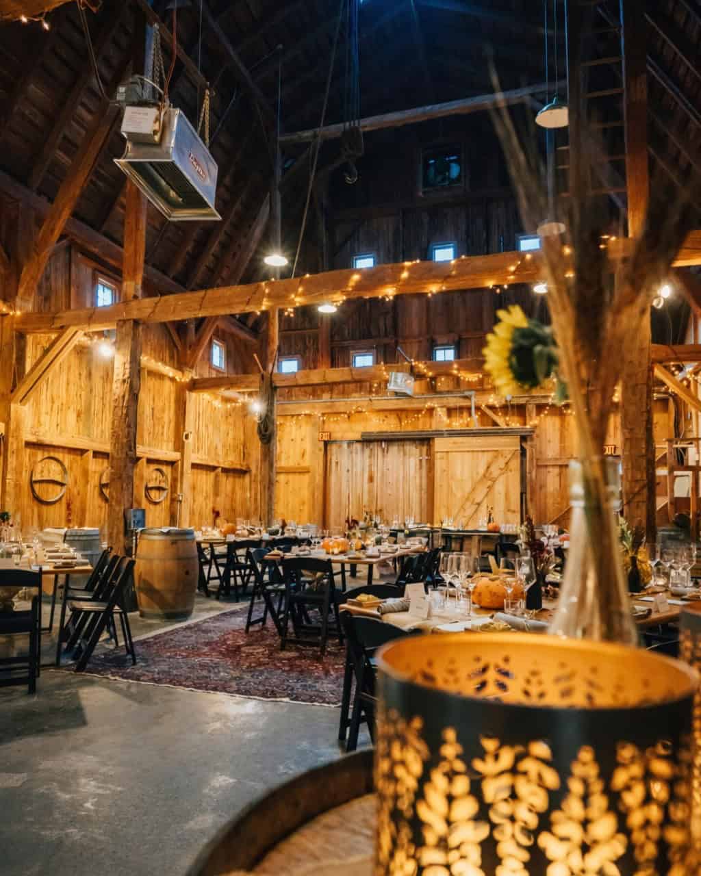 Rustic barn decorated with string lights and set tables for an event, sunflowers in the foreground&mdash;evoking the charm of Finger Lakes Wineries with Lodging.