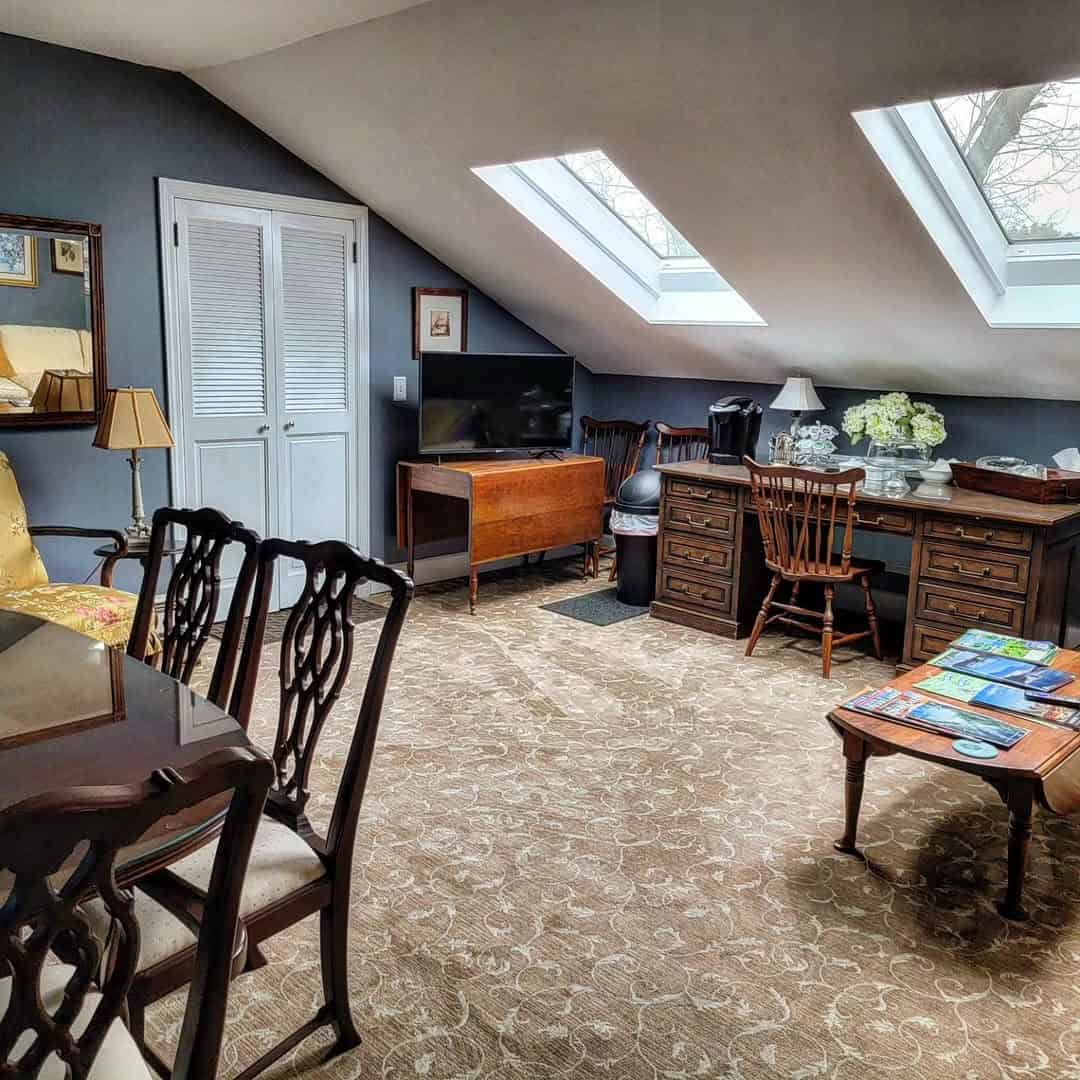 Attic office with skylights, wooden furniture, desk, chairs, and floral carpet in a cozy, well-lit room&mdash;ideal for planning trips to Finger Lakes Wineries with Lodging.