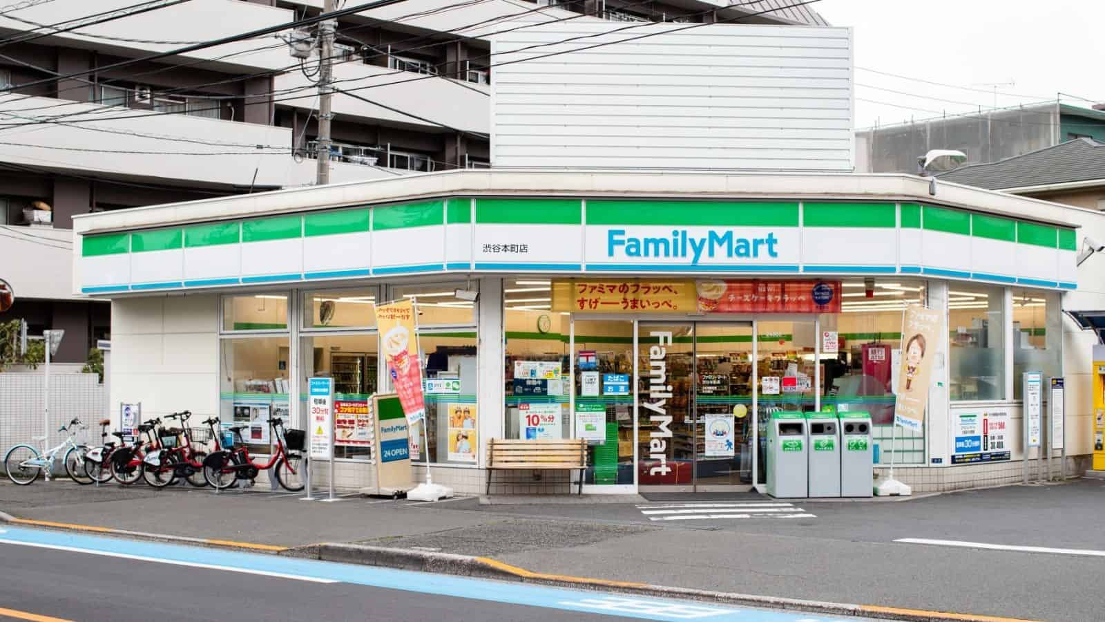 A FamilyMart convenience store with green and blue signage, bicycles parked outside, and posters on the windows.