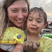 Smiling woman and child in yellow floaties; child has wet hair and sand on face and hand, enjoying a sunny day outdoors at one of the top family resorts.