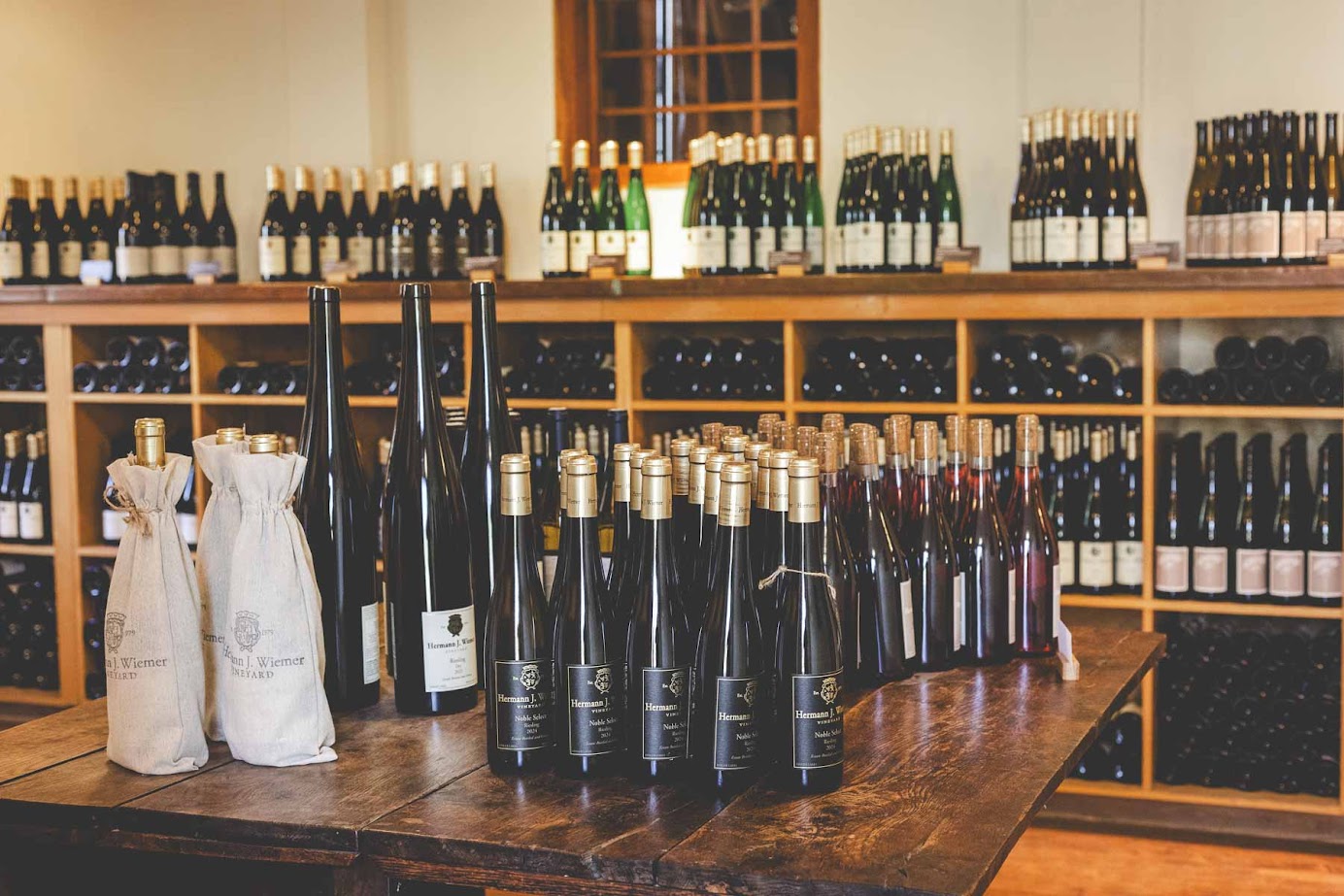 Bottles of wine from the best wineries in Finger Lakes displayed on a wooden table and shelves in a wine shop.