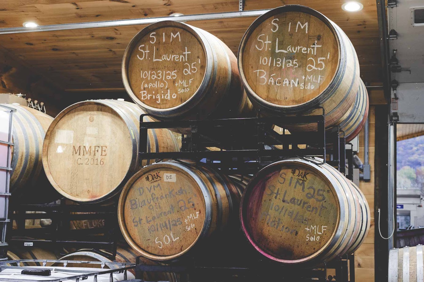 Stacked wooden wine barrels with handwritten labels in a winery storage room, reflecting the craftsmanship found at the best wineries in Finger Lakes.