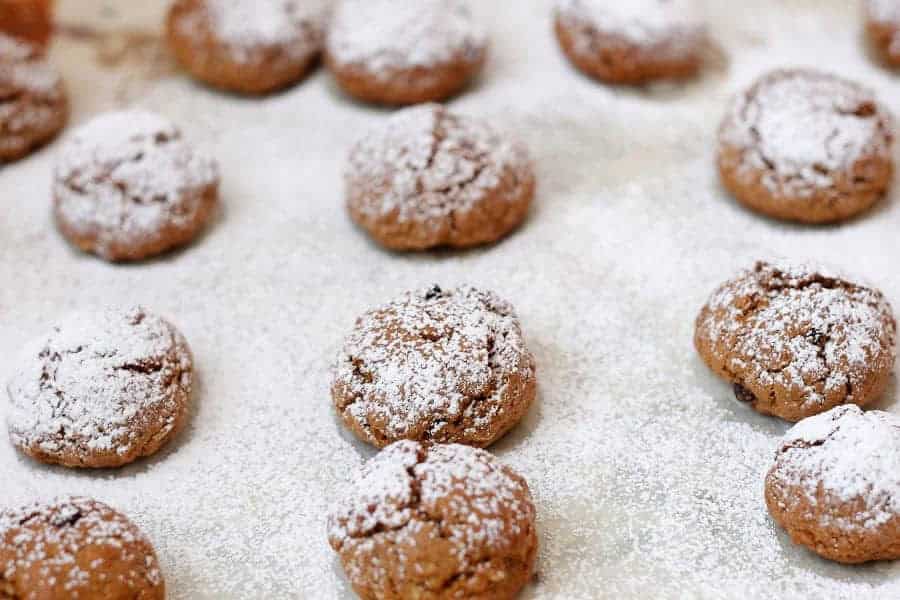 Round cookies dusted with powdered sugar are arranged on a baking sheet, reminiscent of sweet treats often found among vegetarian dishes in Russia.