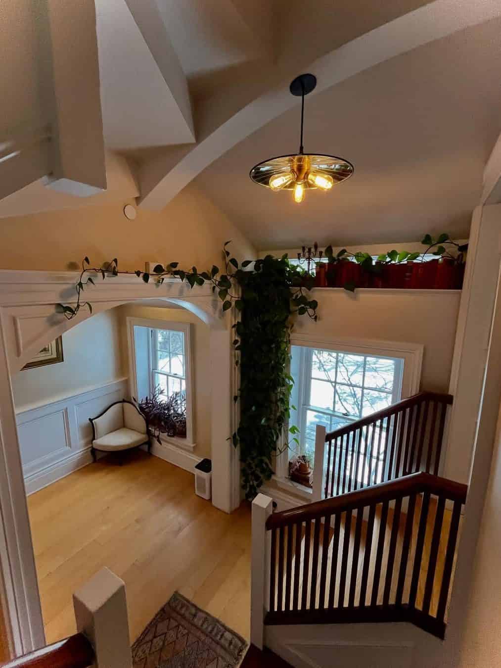 Bright stairwell with large windows, houseplants, wooden railings, and a modern ceiling light fixture—one of the Best Places to Stay in Finger Lakes Near Wineries for a stylish, relaxing escape.