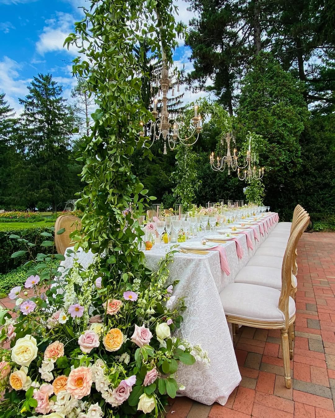 Elegant outdoor table setting with floral arrangements, chandeliers, and wooden chairs on a brick patio—perfect for guests discovering the Best Places to Stay in Finger Lakes Near Wineries.